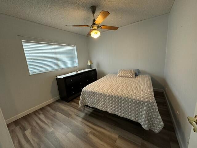 bedroom with hardwood / wood-style flooring, ceiling fan, and a textured ceiling