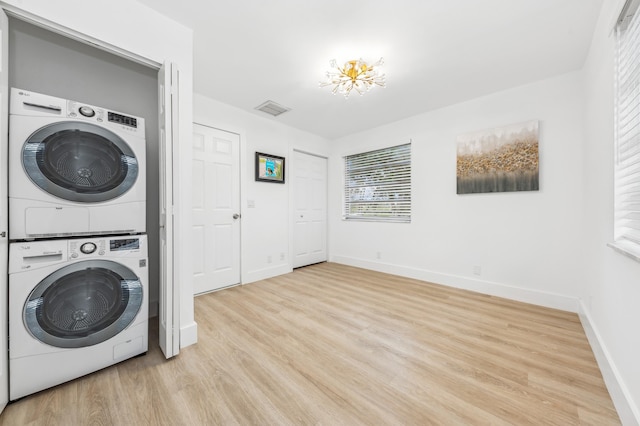 clothes washing area with light hardwood / wood-style flooring and stacked washing maching and dryer