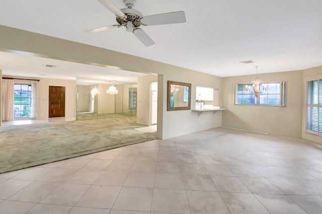 tiled spare room with ceiling fan with notable chandelier