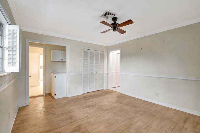 interior space with ceiling fan, light hardwood / wood-style flooring, two closets, and ornamental molding