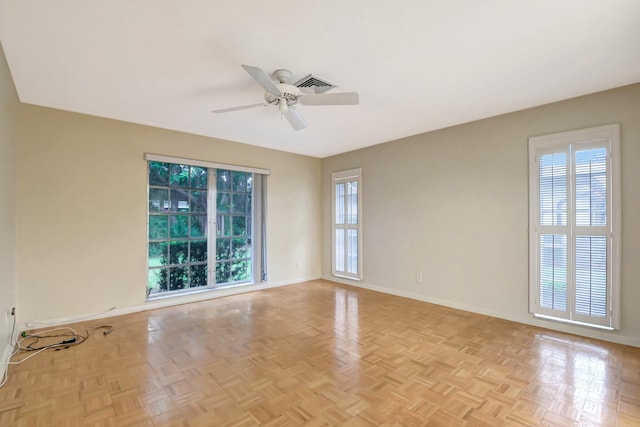 empty room with ceiling fan, plenty of natural light, and light parquet floors