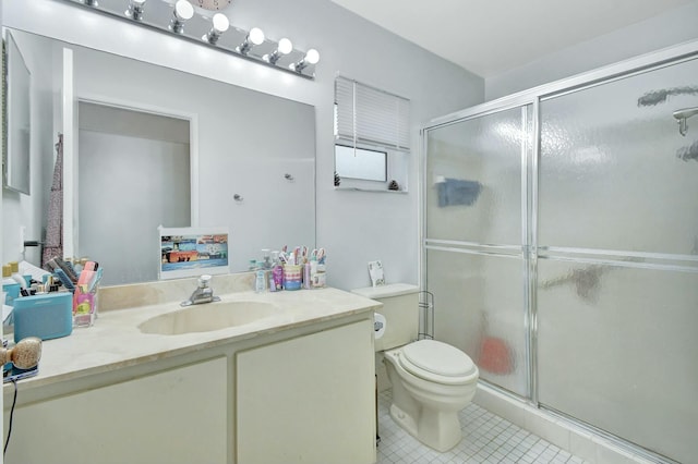 bathroom with tile patterned floors, vanity, a shower with shower door, and toilet