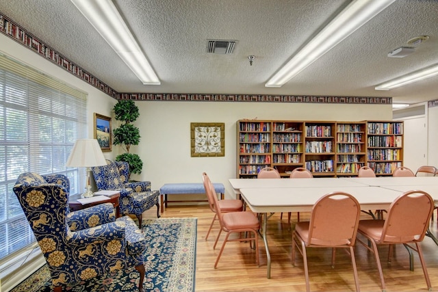 dining space featuring wood-type flooring and a textured ceiling