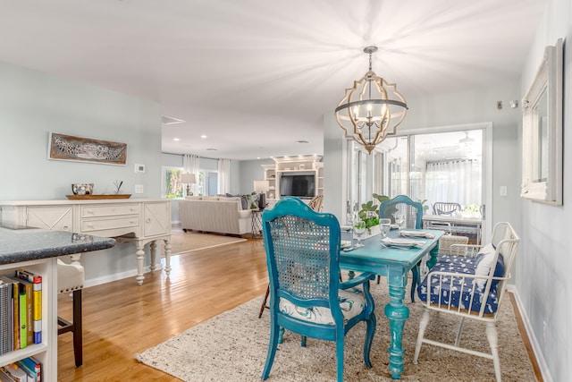 dining space featuring light wood-type flooring and an inviting chandelier