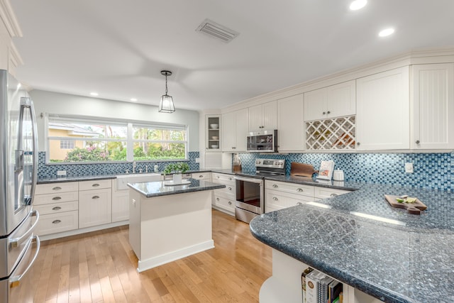 kitchen featuring white cabinets, light hardwood / wood-style floors, a kitchen island, and stainless steel appliances