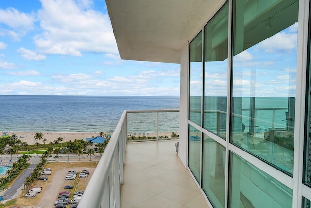 balcony with a water view and a view of the beach