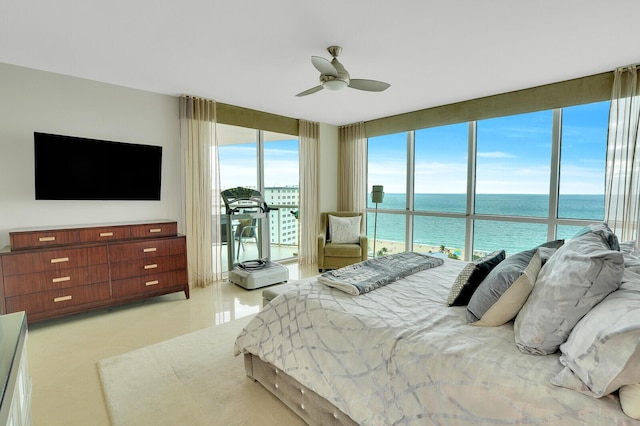 bedroom with expansive windows, ceiling fan, and a water view