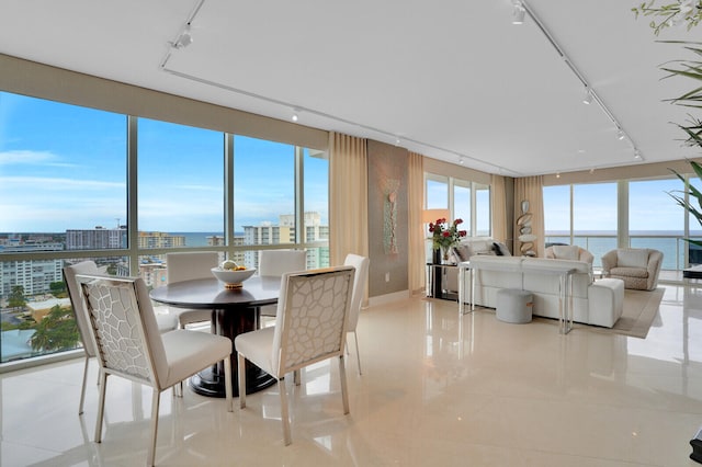 dining room featuring light tile patterned flooring, a water view, and a wall of windows