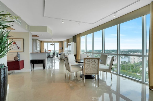 dining room featuring a water view, light tile patterned floors, and a wall of windows