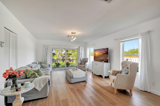 living room featuring a healthy amount of sunlight, light hardwood / wood-style floors, and a chandelier