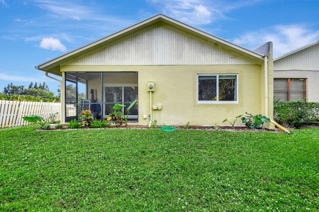 rear view of property with a sunroom and a lawn