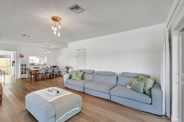 living room with a healthy amount of sunlight, an inviting chandelier, and light hardwood / wood-style flooring