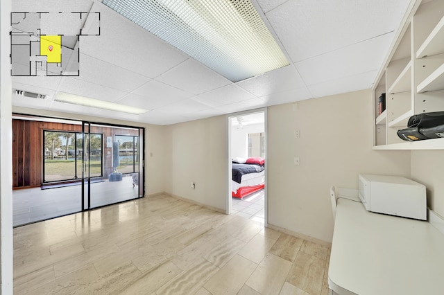 spare room featuring a paneled ceiling and light hardwood / wood-style flooring