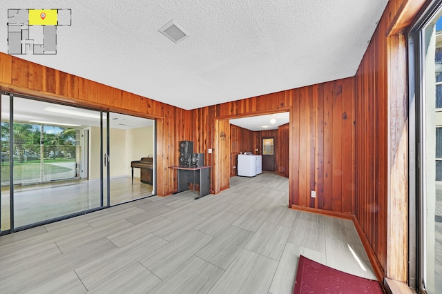 unfurnished room with wooden walls, a textured ceiling, and washer / clothes dryer