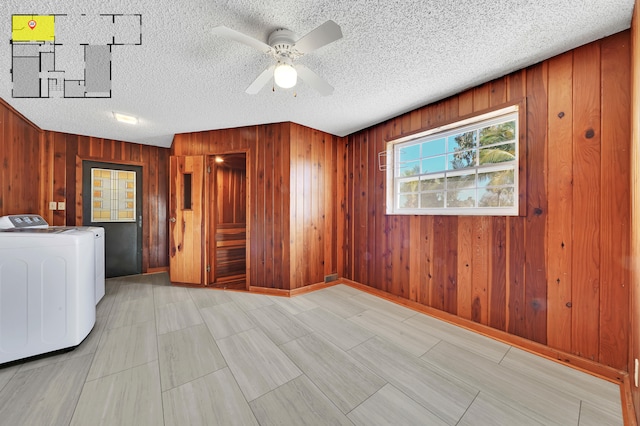 clothes washing area featuring wooden walls, washer and clothes dryer, ceiling fan, and a textured ceiling