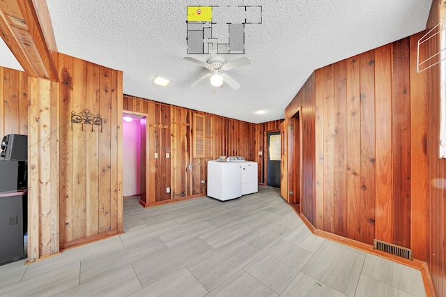 clothes washing area featuring wood walls, ceiling fan, and a textured ceiling