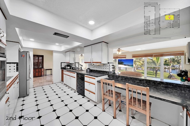 kitchen with decorative backsplash, stainless steel fridge, a raised ceiling, ceiling fan, and white cabinets