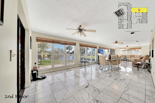 unfurnished living room featuring ceiling fan and a textured ceiling