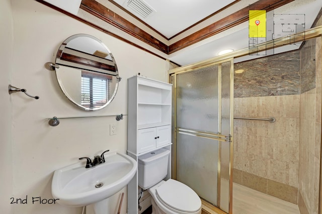 bathroom featuring toilet, a shower with shower door, crown molding, and sink