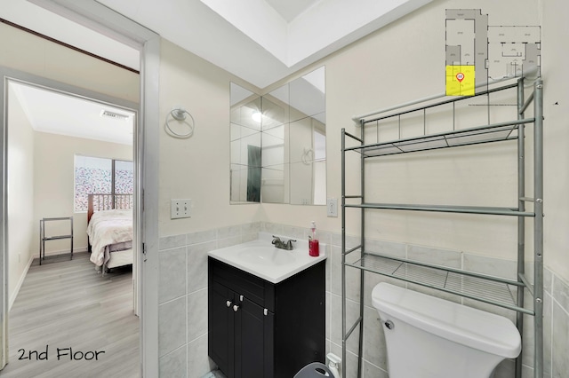 bathroom with toilet, vanity, tile walls, and hardwood / wood-style flooring