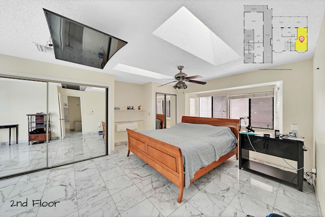 bedroom with ceiling fan, lofted ceiling with skylight, a textured ceiling, and connected bathroom