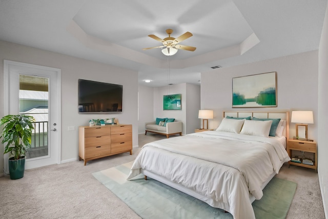 bedroom with ceiling fan, light colored carpet, a tray ceiling, and access to outside