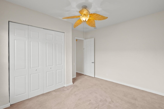 unfurnished bedroom with ceiling fan, a closet, and light carpet