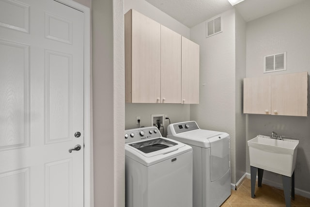 washroom with light tile patterned floors, separate washer and dryer, a textured ceiling, and cabinets