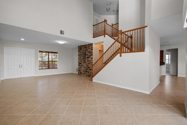 unfurnished living room with light tile patterned floors and a towering ceiling