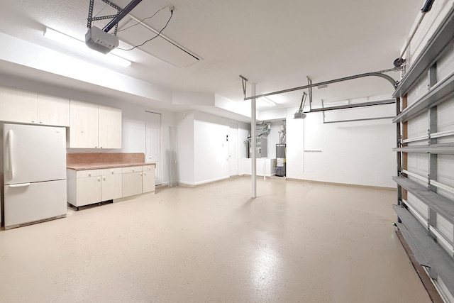 garage with water heater, white fridge, and a garage door opener