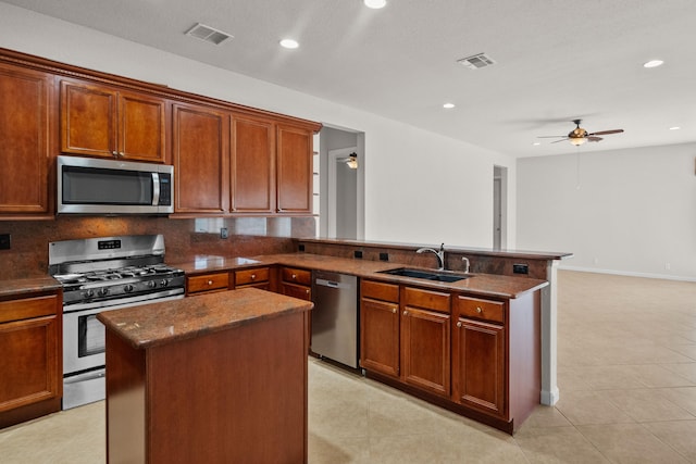 kitchen with a center island, stainless steel appliances, tasteful backsplash, sink, and ceiling fan