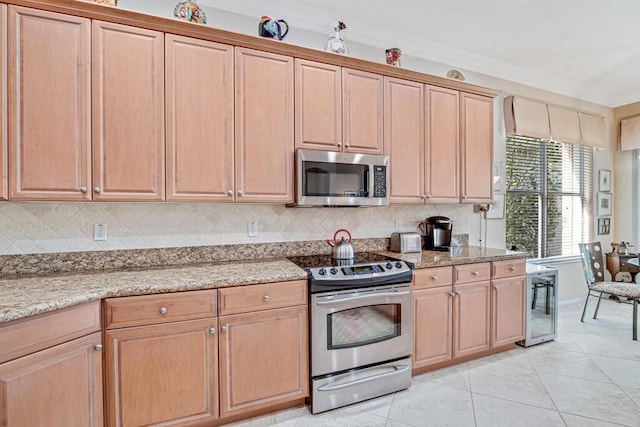 kitchen featuring light stone countertops, backsplash, appliances with stainless steel finishes, light tile patterned flooring, and ornamental molding