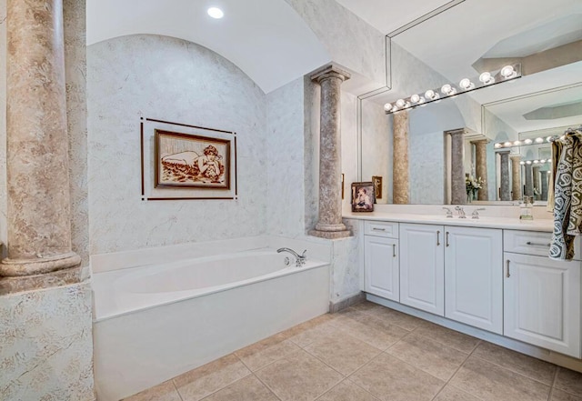 bathroom featuring decorative columns, a tub, tile patterned flooring, and vanity