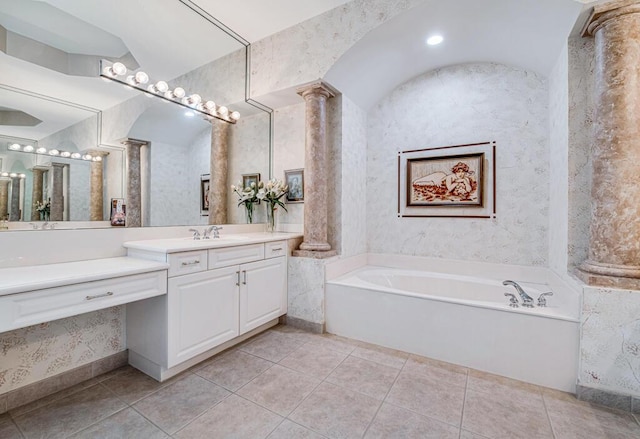 bathroom with tile patterned floors, ornate columns, a washtub, and vanity