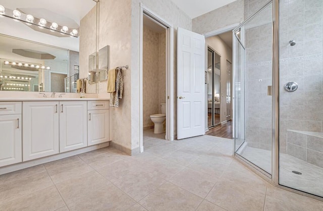 bathroom with tile patterned flooring, vanity, toilet, and a shower with door