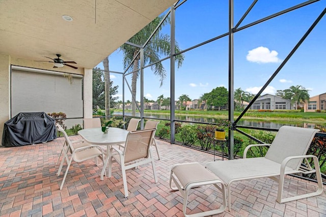 sunroom featuring ceiling fan and a water view