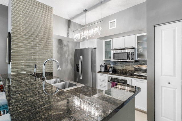 kitchen with white cabinets, sink, appliances with stainless steel finishes, and dark stone counters