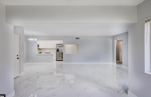 unfurnished living room featuring a textured ceiling and an inviting chandelier