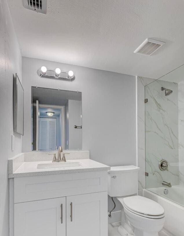 full bathroom with vanity, tiled shower / bath, and toilet