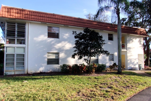 1225 NW 21st St Unit 3506, Stuart, FL 34994 - view of property exterior with stucco siding, a tile roof, and a lawn