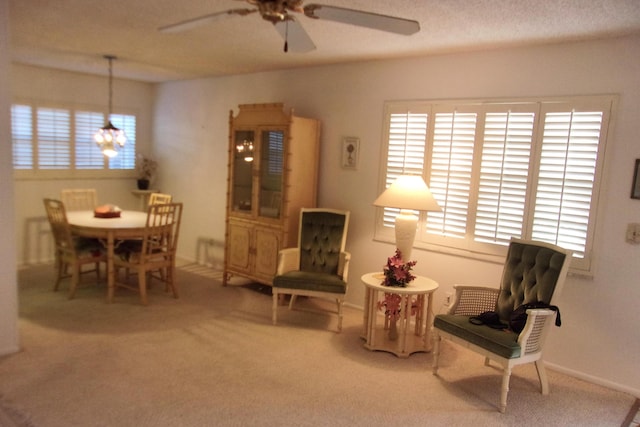 living area featuring carpet flooring and ceiling fan with notable chandelier