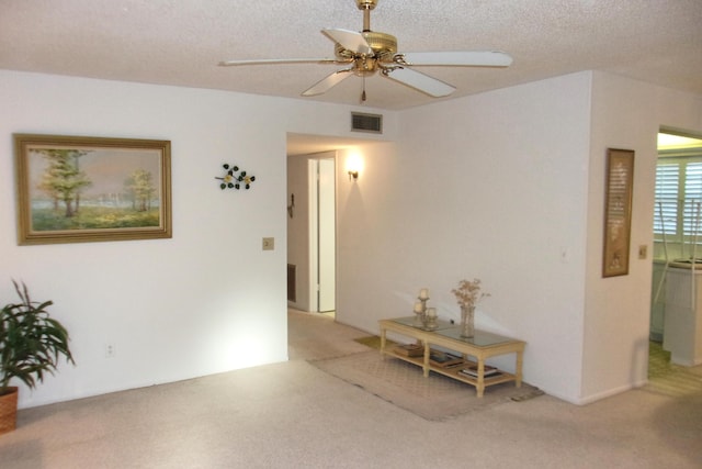 unfurnished room with a textured ceiling, ceiling fan, and light carpet