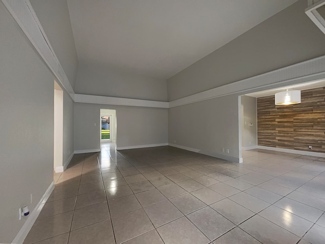 tiled spare room with high vaulted ceiling and wooden walls