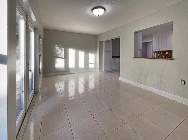 tiled spare room with sink and a textured ceiling