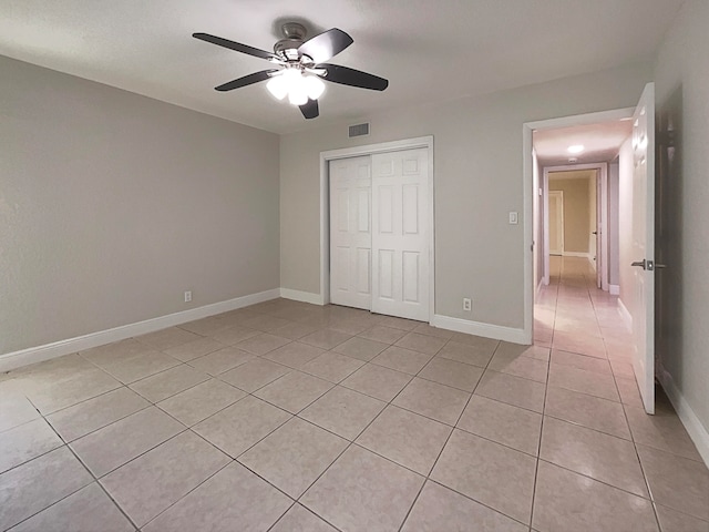 unfurnished bedroom featuring ceiling fan, light tile patterned flooring, and a closet