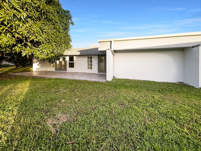 rear view of house featuring a lawn and a patio