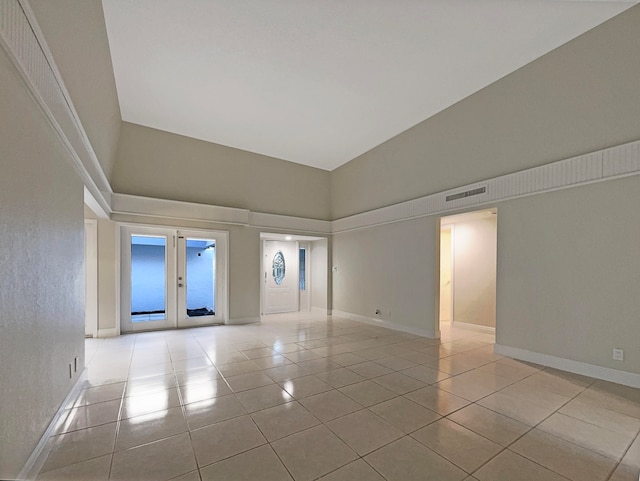 foyer entrance with french doors, high vaulted ceiling, and light tile patterned floors