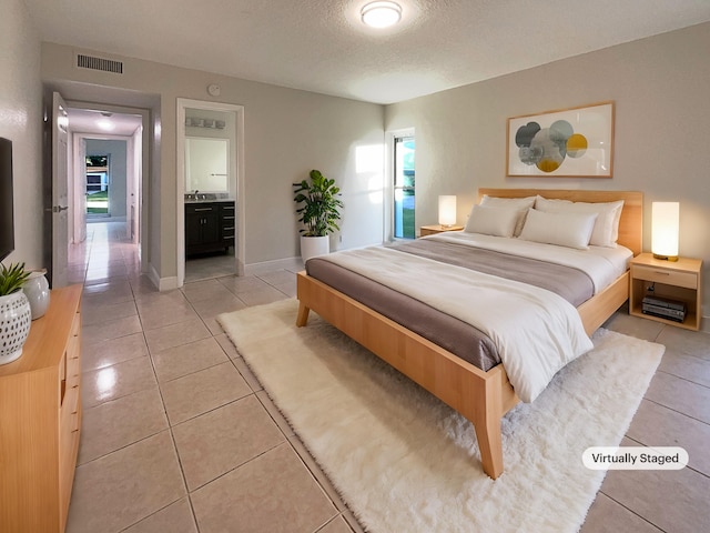 tiled bedroom with connected bathroom and a textured ceiling