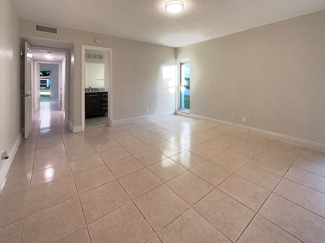 tiled empty room with a textured ceiling