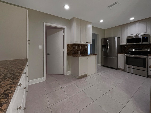 kitchen with decorative backsplash, dark stone countertops, light tile patterned floors, and stainless steel appliances